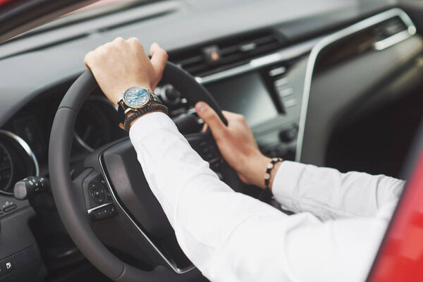 A businessman rides his car, moves on the wheel. A watch on hand in a man's divorce