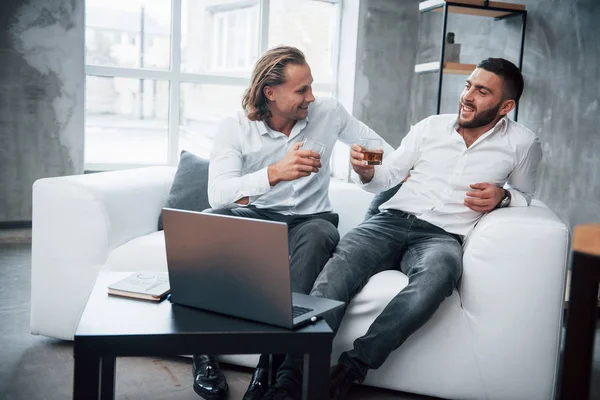 Celebrando Éxito Dos Hombres Negocios Sentados Frente Portátil Hablando Sus — Foto de Stock