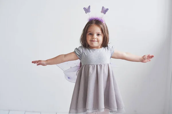 飛べると思う可愛いです女の子でザフェアリー衣装で部屋に立って白い背景 — ストック写真