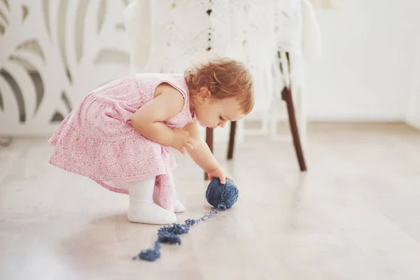 幼少期のコンセプト カラフルな糸で可愛いドレス遊びで赤ちゃんの女の子 白ヴィンテージ子供部屋 — ストック写真