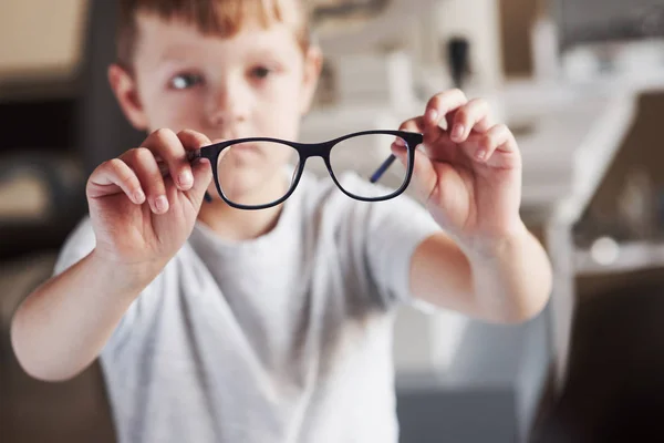 写真を中心に小さな男の子は医者のオフィスで新しい眼鏡を持っています — ストック写真
