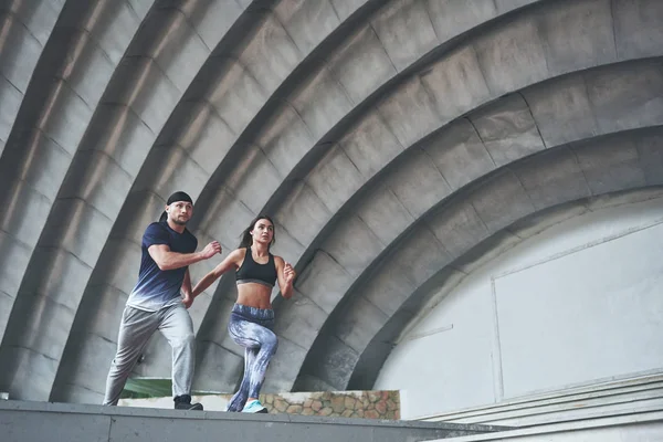 Young happy sports couple in the city street, performing parkour