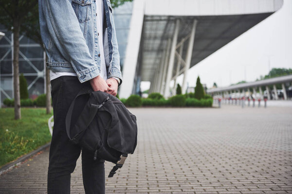 Young handsome man with a bag on his shoulder in a hurry to the airport