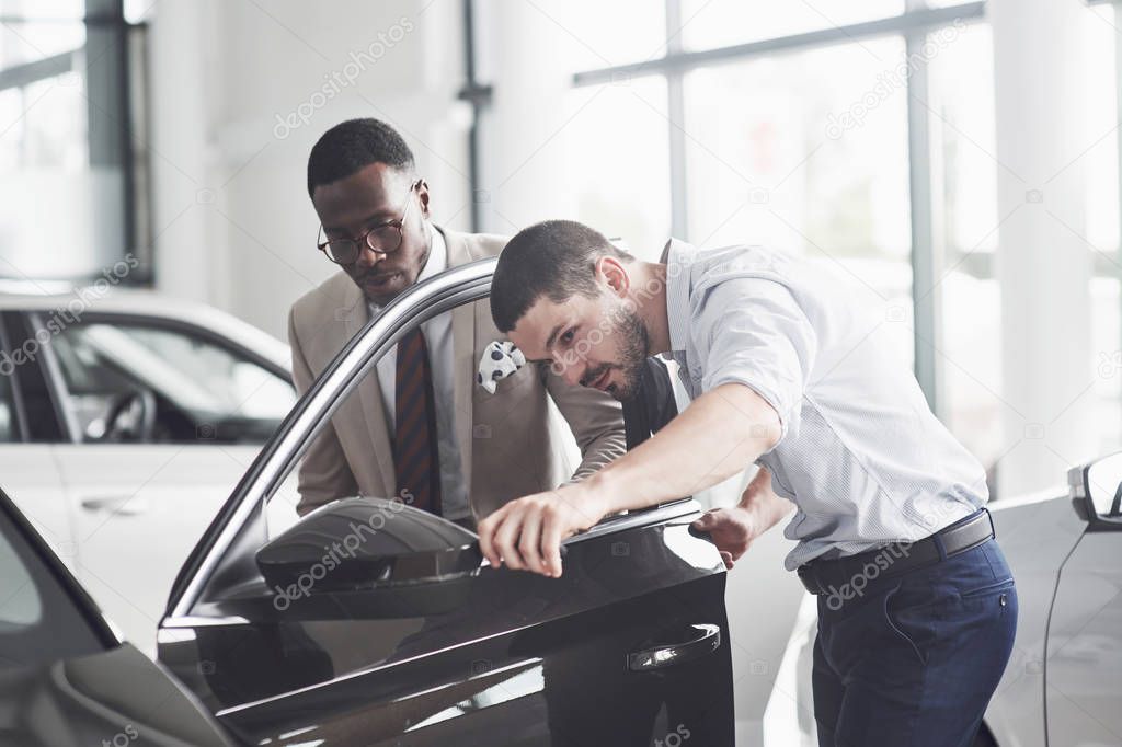 An African man who buys a new car checks a car talking to a professional vendor