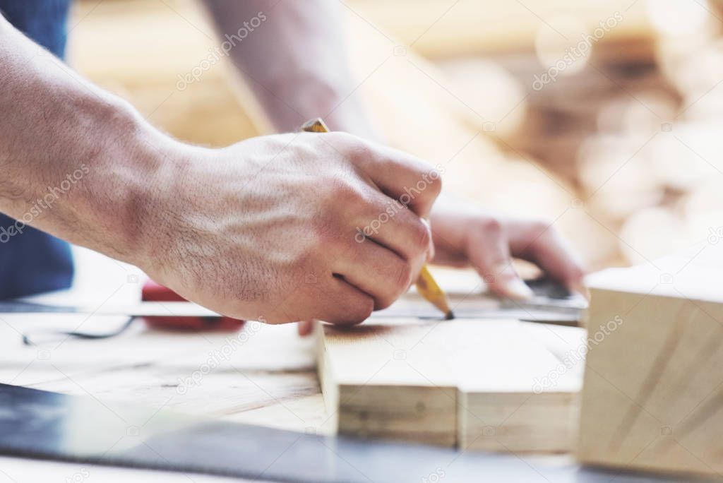 A carpenter in working clothes and a small business owner takes a wooden board with a ruler and pencil