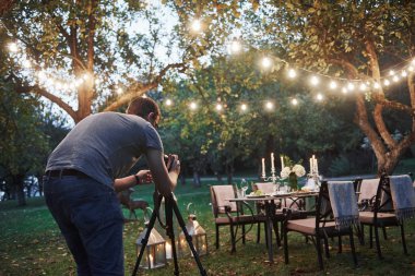 Gözlüklü profesyonel fotoğrafçı servis masasının fotoğrafını çekiyor..