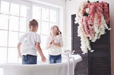Çocuk ev banyosunda gül yapraklarıyla oynuyor. Küçük kız ve oğlan birlikte eğlence ve neşe saçıyorlar. Çocukluk kavramı ve hayallerin gerçekleştirilmesi, fantezi, hayal gücü..