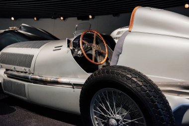 Gri retro spor coupe cabriolet iç ve kaput yan görünümü: ahşap direksiyon, gösterge paneli, ayna, alaşım diskler ve arka planda klasik araba