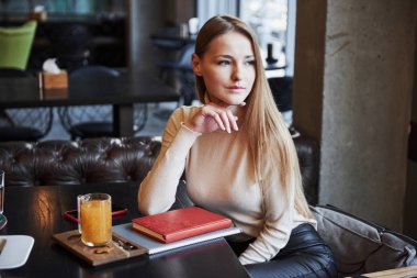 Yana bakıyor. Restorandaki sakin kız. İç, not defteri ve kırmızı kitap siyah masanın üstünde..