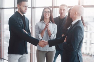 Ofisteki bir toplantıda el sıkışan iki kendine güvenen iş adamı, başarı, anlaşma, selamlama ve ortaklık kavramı.