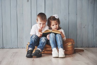 Büyük seyahate hazırız. Küçük mutlu kız ve çocuk ilginç bir kitap okuyor büyük bir evrak çantası taşıyor ve gülümsüyor. Seyahat, özgürlük ve hayal gücü kavramı.