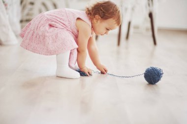 Çocukluk konsepti. Renkli iplikli, şirin elbiseli kız oyunu. Beyaz mahsul çocuk odası.