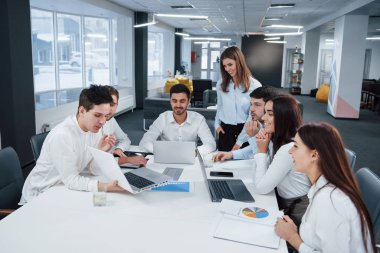 İyi sonuçlar veriyor. Ofisteki bir grup genç serbest çalışan sohbet ediyor ve gülümsüyor..