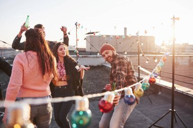 Güzel gün ışığı. Çatıda en sevilen şarkıları söylerken ellerinde alkol ve arkadaşlarla.