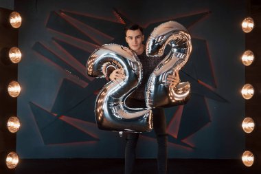 Arka planda bir stüdyoda poz veren yakışıklı bir çocuğun portresi.