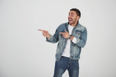 Gözlüklü mutlu sakallı adam gülümseyerek kameraya bakıyor ve iki parmağı beyaz arka planda izole bir şekilde fotokopi alanını gösteriyor..