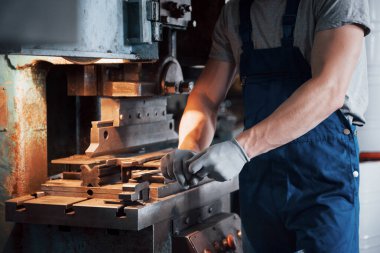 Büyük bir metal fabrikasında kasketli genç bir işçinin portresi. Makinelere hizmet eden mühendis, gaz ekipmanları için parça üretiyor..