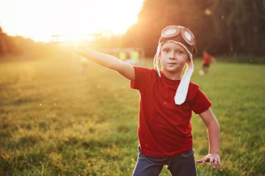 Pilot kasklı mutlu çocuk tahta bir oyuncak uçakla oynuyor ve uçmayı hayal ediyor..