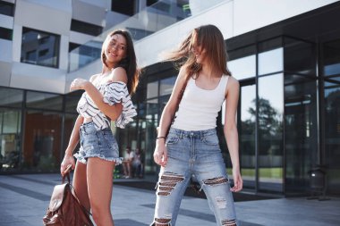 Üniversitenin kampüsünün yakınında sırt çantalı iki güzel mutlu öğrenci kız. Eğitim ve eğlence kavramı.