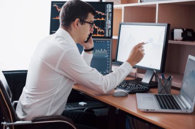 Tişörtlü borsacı ekran ekranlarıyla izleme odasında çalışıyor. Menkul Kıymetler Borsası Eski Finans Grafik Kavramı. İşadamları online hisse senedi ticareti yapıyor.