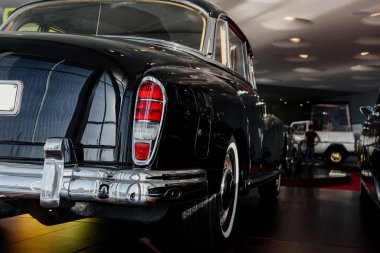 Siyah retro-birinci sınıf bir arabanın arka ve yan görüntüsü sağ arka lambası, krom tamponu, kahverengi zemin üzerinde beyaz duvar lastiği.