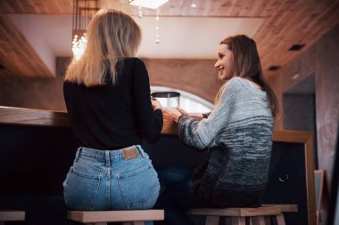 İki arkadaş bir tablo sohbet otururken bir kafede birlikte kahve keyfi.