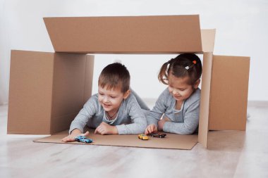 Bebek kız ve erkek çocuk kız kardeşi karton oynayan çocuk odasında kutuları.