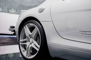 Sağ beyaz ışıklı alaşım tekerleği ve düşük profilli lastiği olan modern spor arabanın yan görüntüsü bulanık arka planda krom yakıt deposu kapağı.