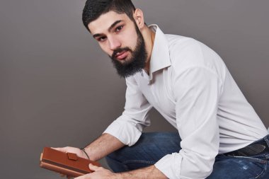 Elinde kitap olan dişlek, sakallı, yakışıklı bir adamın portresi..