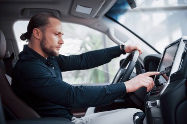 Kendine güvenen genç işadamı yeni arabasının direksiyonunda oturuyor..