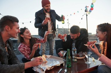 Yemek vakti. Çatıdaki partide pizza yiyorum. İyi arkadaşlar hafta sonları lezzetli yiyecekler ve alkolle vakit geçirir..