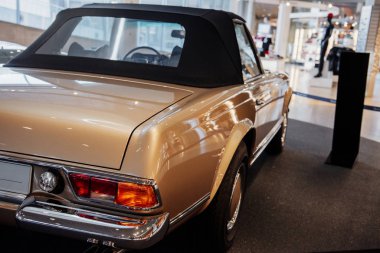 Arka ve yan görünümü bej renkli eski bir arabanın sağ krom arka lambası, tamponu ve tekerleği kapalı bir lastiğin üzerinde..