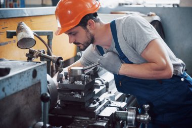 Başlık takmış deneyimli bir operatör. Metal endüstrisi konsepti profesyonel mühendis metal işçisi imalat atölyesinde Cnc değirmen makine merkezi işletiyor.