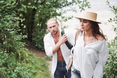 Sırt çantalı iki doğa yürüyüşçüsü. Bir yaz günü yürürken el ele tutuşan erkek ve kadın..