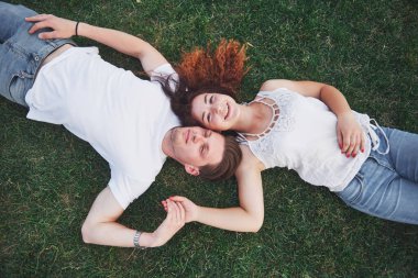 Parktaki çimlerin üzerinde yatan romantik iki genç insan. Mutlu görünüyorlar. Yukarıdan görüntüle