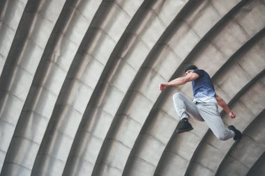 Genç adam şehrin kentsel alanında parkur atlayışı yapıyor güneşli bahar günü