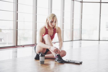 Eğitimden sonra rahatlatıcı. Güzel genç kadın uzak egzersiz mat spor salonunda otururken arıyor görünümünü.