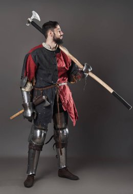 Gri arka planda ortaçağ şövalyesi. Zincirli zırhlı, kırmızı, siyah elbiseli ve savaş baltalı zalim, kirli yüzlü bir savaşçı portresi..