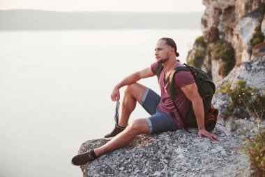 Kayanın tepesinde kamp ateşiyle başarılı bir yürüyüşçü. Dağlar ve kıyı boyunca seyahat, özgürlük ve aktif yaşam tarzı konsepti.