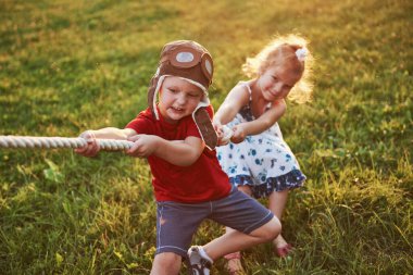 Oğlan ve kız halat çekiyorlar ve parkta çekiştiriyorlar..