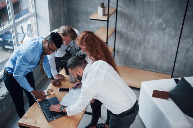 Plan üzerinde çalışan dört genç işadamı defter kullanıyor..