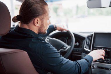 Kendine güvenen genç işadamının yeni arabasının direksiyonunda oturması..