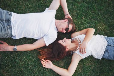Parktaki çimlerin üzerinde yatan romantik iki genç insan. Mutlu görünüyorlar. Yukarıdan görüntüle