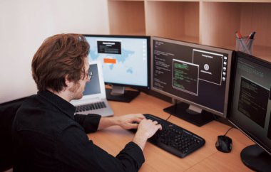 Yazılım ofiste birçok monitör ile masaüstü bilgisayarda çalışan erkek programcı şirket geliştirmek. Web sitesi tasarım programlama ve kodlama teknolojileri.