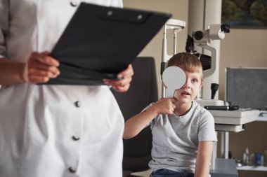 Mektup okuyorum. Gözcü muayenehanesinde hamilelik testi yapıyorlar. Doktor verileri not eder.