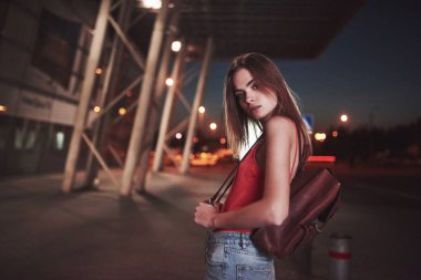 Omuzlarının arkasında sırt çantası olan genç ve güzel bir kız sıcak bir yaz akşamında havaalanının ya da tren istasyonunun yanındaki sokakta duruyor. Yeni geldi ve bir taksi ya da arkadaşlarını bekliyor..