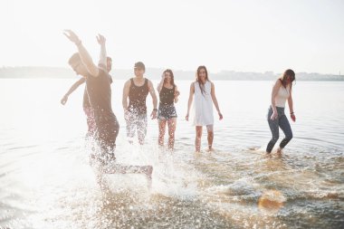 Mutlu arkadaşlar kumsalda eğlenir - Gençler yaz tatillerinde açık havada oynarlar.