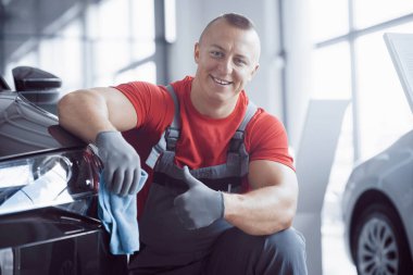 Adam mikrofiberi elinde tutuyor ve arabayı cilalıyor. Yeni makine satışa hazır..