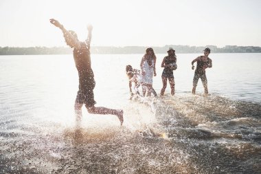Mutlu arkadaşlar kumsalda eğlenir - Gençler yaz tatillerinde açık havada oynarlar.