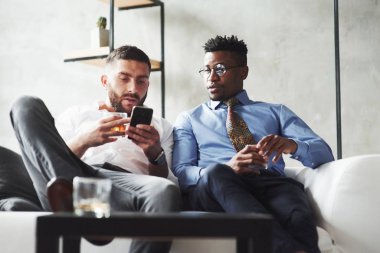 Ön manzara. Uluslararası meslektaşlar beyaz koltukta oturup iş malzemelerine bakıyorlar..